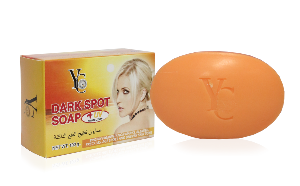An orange oval bar of soap next to its yellow and orange packaging box, both featuring the brand logo 'YC' and the text 'DARK SPOT SOAP'.