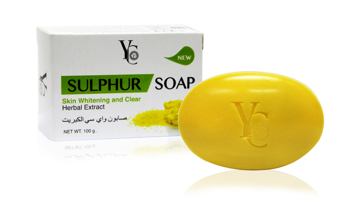 Yellow sulphur soap bar next to its white packaging box with green and black text, on a white reflective background.