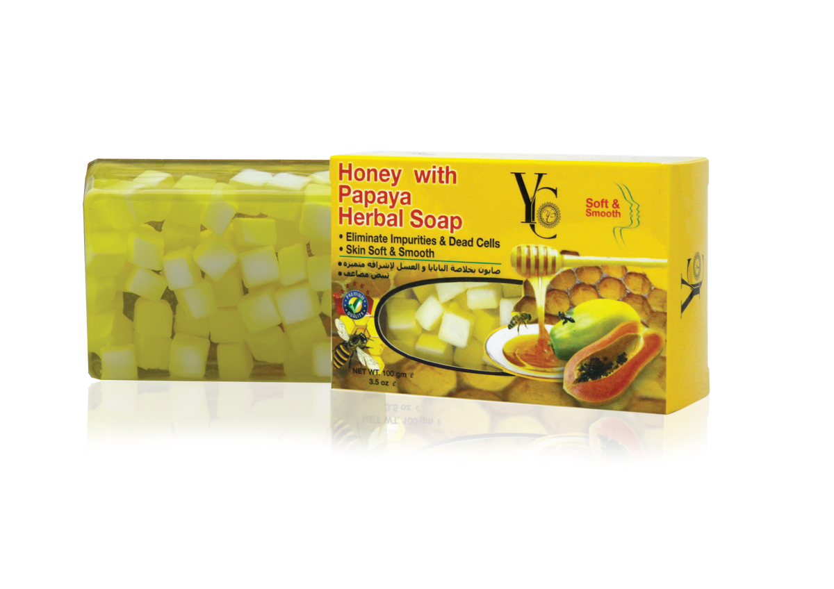 A bar of Honey with Papaya Herbal Soap shown with its yellow retail box. The soap bar is filled with yellow and white cubical suds, and the packaging features illustrations of honey, a papaya, and a bee.